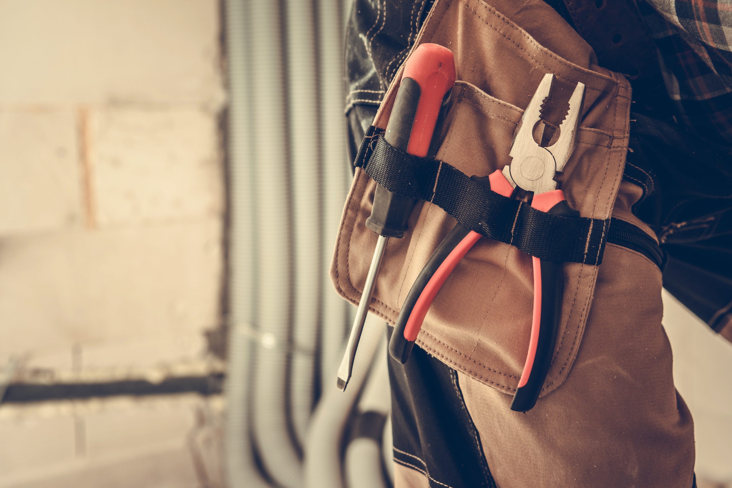Construction Contractor Worker Tools Close Up. Pliers and Screwdriver Attached to Clothing. Industrial Theme.
