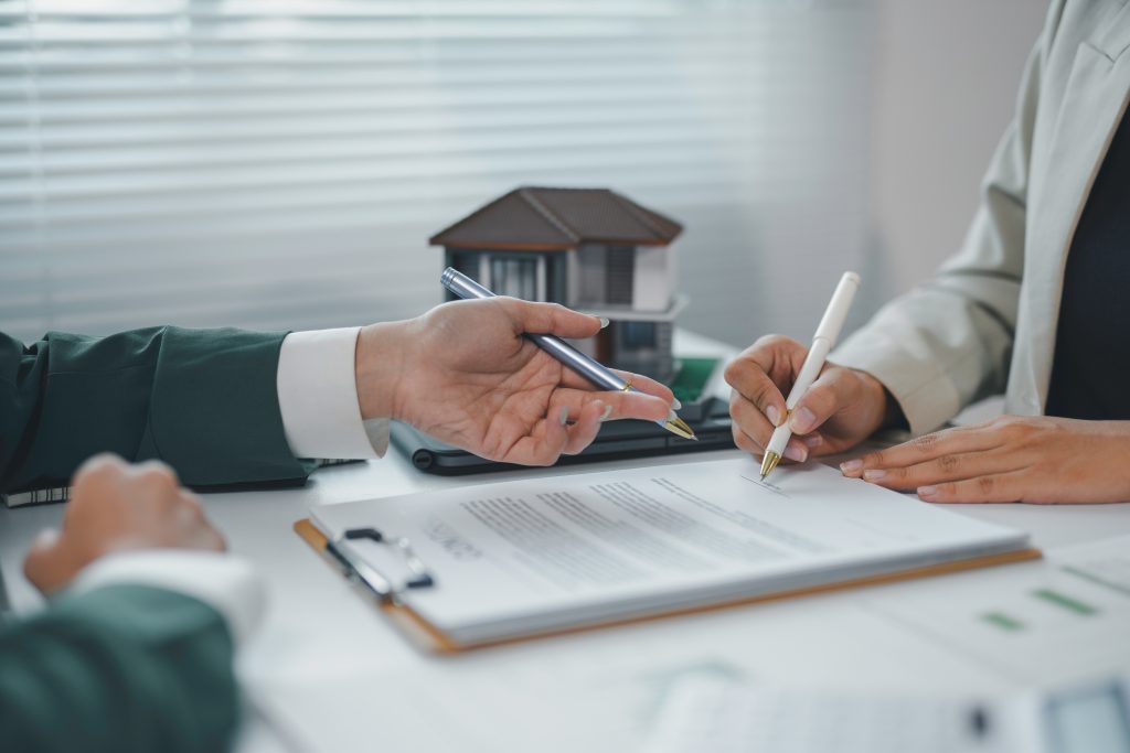 Client signing a contract for a new house, real estate agent pointing at signature place