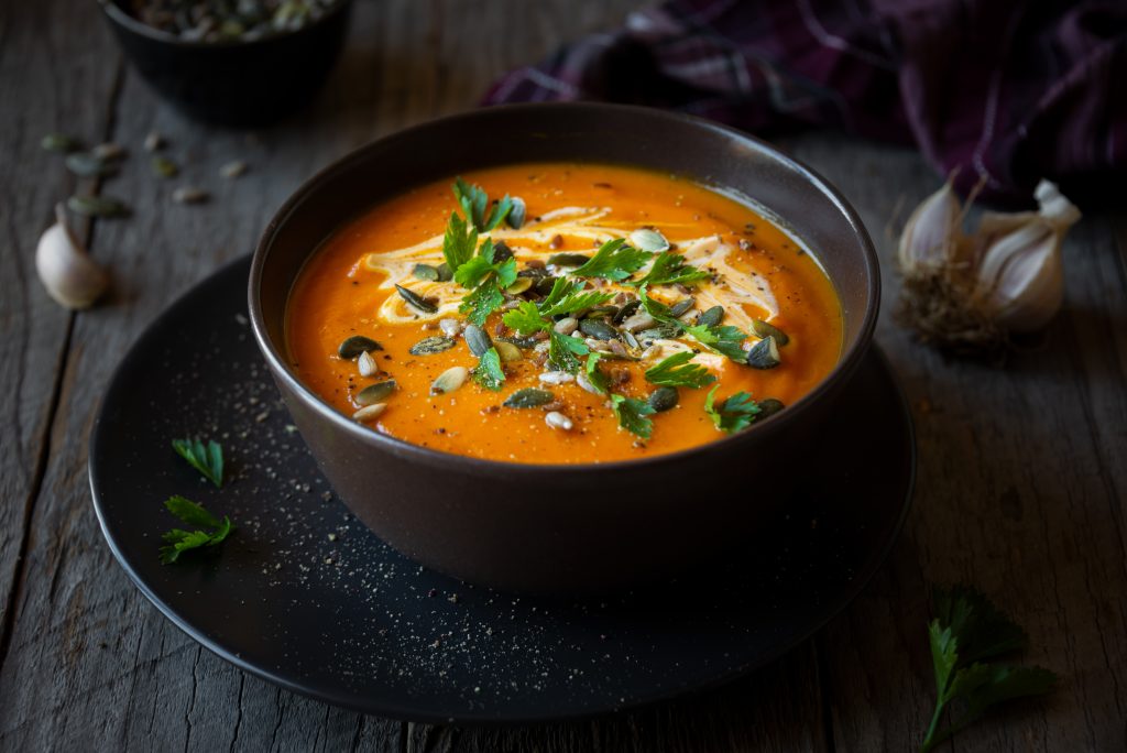 Pumpkin soup with cream, parsley and pumpkin seeds on dark